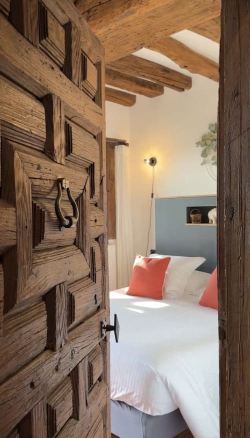 Portes rustiques en bois ouvrant sur une chambre pittoresque avec coussins rouges et poutres apparentes au Paradis de Lucile, Giverny
