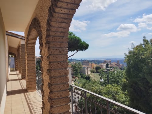 Terrazza con colonne in terracotta che si affaccia sulla campagna di Campagnano di Roma e edifici storici