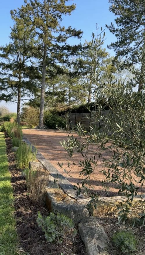 Allée du jardin bordée d'oliviers et de pierre au Paradis de Lucile près de Giverny