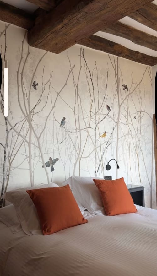 Chambre douillette du gîte Le Paradis de Lucile à La Roche Guyon avec fresque forestière, poutres apparentes et coussins orange