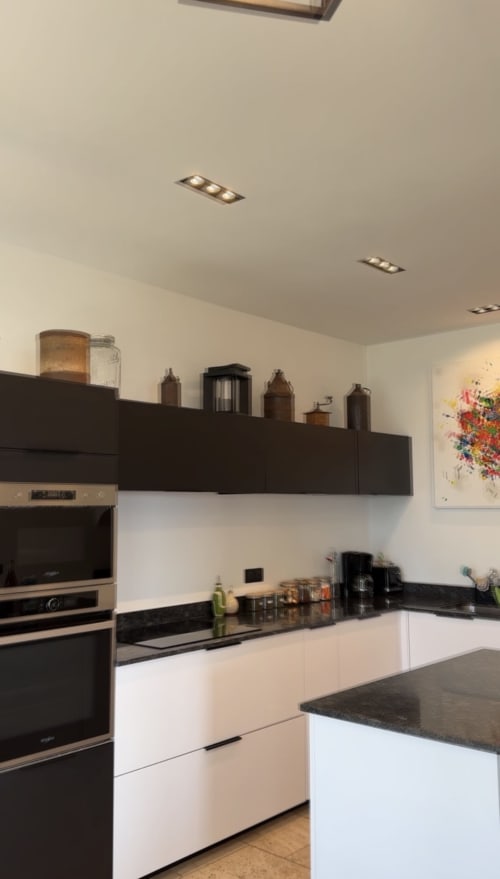 Cuisine moderne en noir et blanc avec appareils en acier inoxydable au gîte Le Paradis de Lucile à La Roche Guyon