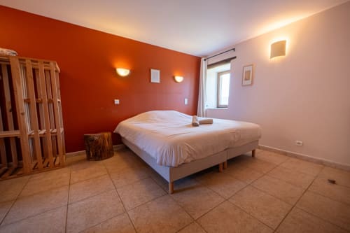 Spacious Lou Cerisier bedroom at Eco-hameau Lou Rey with red accent wall, queen bed, tile flooring, and mountain views from