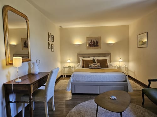 Elegant bedroom at Château de Ribourdin with garden view, featuring a comfortable bed, desk, and warm ambient lighting