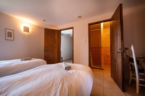Modern hostel room at Lou Cerisier, Eco-hameau Lou Rey in Le Collet de Dèze with twin beds, wooden doors, and bathroom with