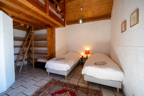 Cozy shared room at Eco-hameau Lou Rey hostel with twin beds, wooden loft, and mountain views in Le Collet de Dèze