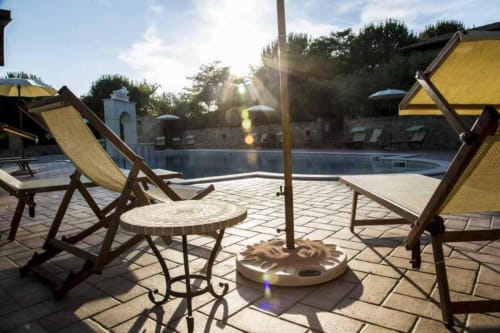 Poolside seating area at Agriturismo Colle Mura with yellow umbrellas, deck chairs, and umbrella table in Gualdo Tadino