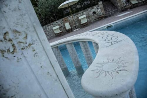 Pool area at Agriturismo Colle Mura with sun-decorated loungers, umbrellas, and stone terrace in Gualdo Tadino