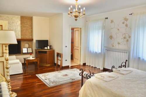 Elegant bedroom at Agriturismo Colle Mura in Gualdo Tadino with wooden floors, fireplace, and classic furnishings
