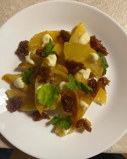 Elegant plated dish with roasted potatoes, crispy meat, creamy sauce, and fresh parsley at Agriturismo Colle Mura in Gualdo