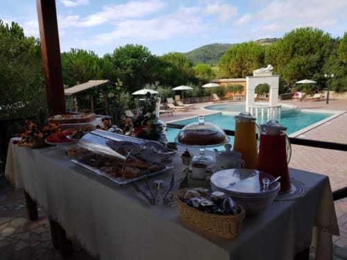 Outdoor buffet setup at Agriturismo Colle Mura with turquoise pools and Tuscan hillside views
