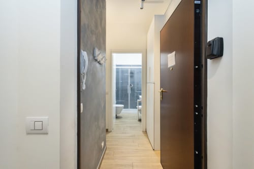 Современный коридор апартамента 18C в Magnolia Apartments Милан с паркетом, коричневой дверью и видом на ванную комнату