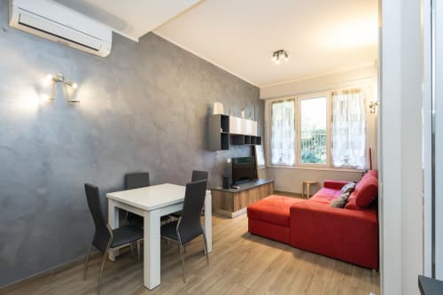 Современная гостиная в Magnolia Apartments Милан с красным диваном, обеденным столом и окнами с видом на сад