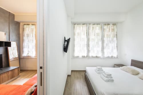 Современная спальня в Magnolia Apartments Milan с белой кроватью, паркетом и видом на сад