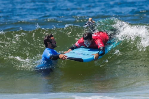 Instrutor de surf ensinando hóspede na pousada Vila Alexandra em Costa da Caparica, Portugal