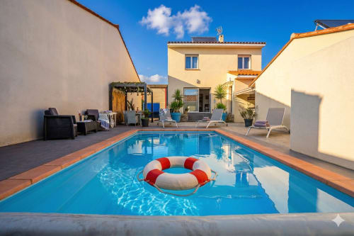 Villa Chez Domi à Canet-en-Roussillon : piscine bleue, bouée de sauvetage rouge, terrasse et ambiance méditerranéenne ensoleillée