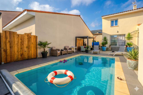 Villa ensoleillée avec piscine, bouée de sauvetage rouge et blanche, transats et maison jaune à Canet-en-Roussillon
