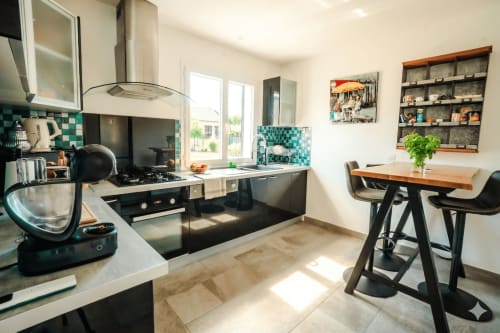 Cuisine moderne avec carrelage turquoise, électroménagers noirs, table à manger et rangements à la villa Chez Domi, Canet-en-Roussillon