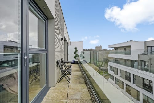 Modern balcony at luxury Stevenage apartment with chair, contemporary railings, and views of residential complex