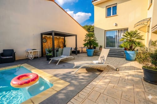 Terrasse ensoleillée avec piscine bleue, chaises longues et villa jaune chez Domi à Canet-en-Roussillon
