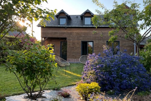 Jardin cottage moderne à Destination Étretat avec fleurs violettes, mobilier de jardin et architecture bois contemporaine