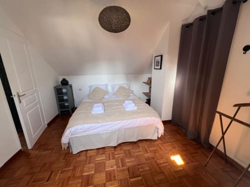 Chambre douillette du gîte Destination Etretat avec lit double, parquet, rideaux marron et lampe suspendue