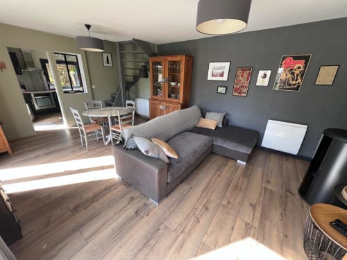 Salon moderne avec canapé gris, table à manger, parquets en bois et vue sur le jardin du gîte Destination Etretat