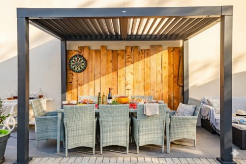 Salle à manger couverte avec mobilier en rotin à la villa Chez Domi, Canet-en-Roussillon, avec fond boisé et fléchettes