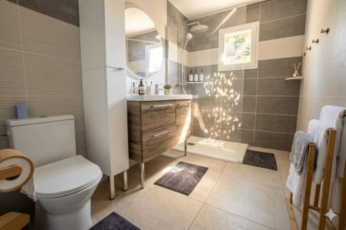 Salle de bain moderne avec vasque, douche, toilettes et porte-serviettes à la villa Chez Mara à Canet