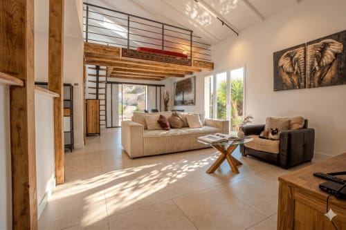 Spacieux séjour de la villa Chez Mara à Canet-en-Roussillon avec canapé beige, poutres en bois et mezzanine