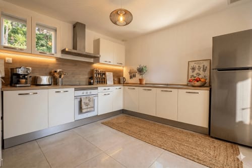 Cuisine moderne de la villa Chez Mara à Canet-en-Roussillon, équipée de meubles blancs, d'appareils en inox et d'un carrelage