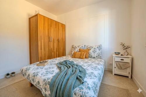 Chambre lumineuse à la villa Chez Mara, Canet-en-Roussillon avec armoire en bois, literie fleurie et table de nuit blanche