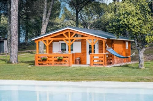 Orange wooden bungalow Limão at Chalet Do Lago in Montargil, Portugal, nestled among pine trees with pool view