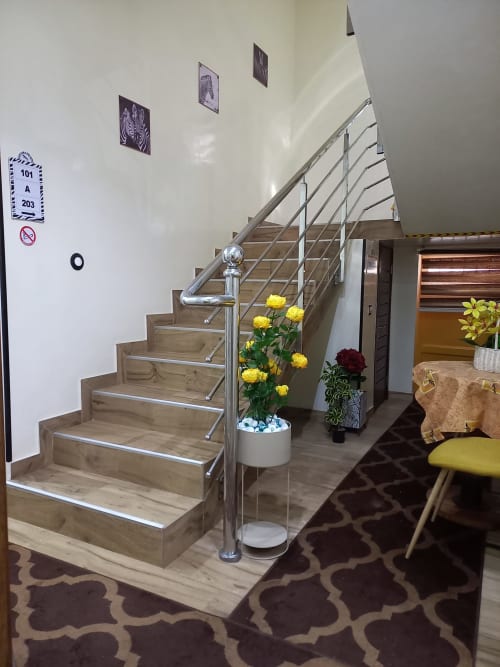 Escalier contemporain avec rampes métalliques à l'hôtel Zebra Résidence à Bambilor, orné de fleurs jaunes et de plantes