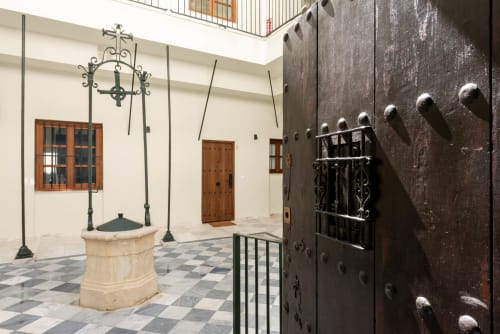 Patio de estilo colonial en Puerto Santa María con puerta de madera oscura ornamentada, paredes blancas, linterna decorativa y diseño cuadriculado