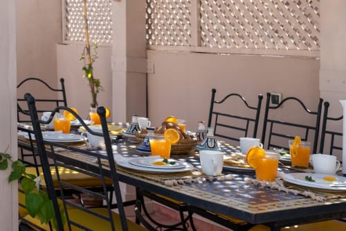 Table élégante du Riad Dabachi Tala'lou à Marrakech avec jus d'orange, couverts et décor géométrique