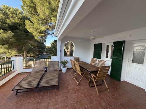 Spacious terrace at Can Jaime apartment in Menorca with dining table, loungers, sea views, and green shutters