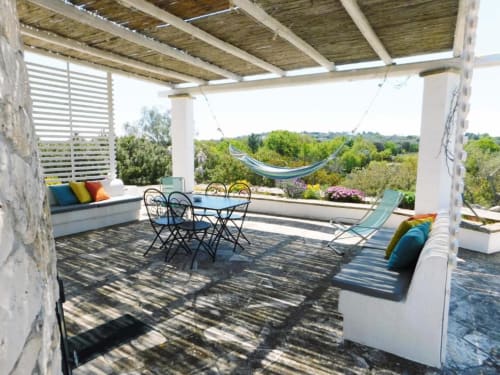 Ampia terrazza di Pietra & Luce Ada Trullo a Ostuni con tavolo da pranzo, amaca e vista sulla campagna