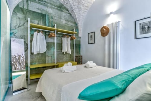 Appartamento in stile Ostuni a Pietra & Luce con letto, biancheria turchese, attaccapanni bianco e soffitto in pietra ad arco