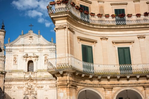 Architettura barocca ornamentale della struttura ricettiva Pietra & Luce a Ostuni, con facciata in pietra bianca e ferro battuto