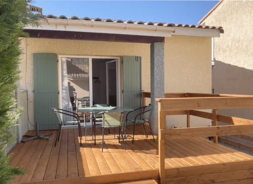 Terrasse ensoleillée de l'appartement Le Vallon des Sources avec terrasse bois, table de repas et vue sur le jardin à Digne-les-Bains