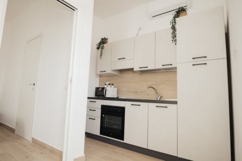 Cucina moderna nella Double Room di Casa del Sole B&B a Foggia con mobili bianchi, piano nero e rivestimento in legno