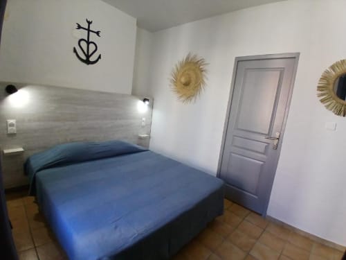 Blue double bed in comfortable hotel room at Hôtel Quai d'Azur in Le Grau-du-Roi with modern decor