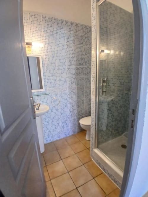 Modern bathroom at Hôtel Quai d'Azur with mosaic tile walls, walk-in shower, sink and toilet