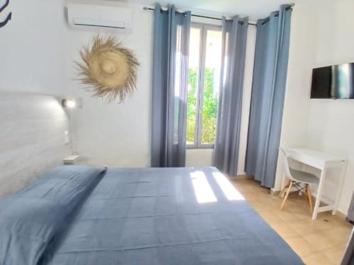 Modern bedroom at Hôtel Quai d'Azur with blue bed, blue curtains, desk, wall art, and wooden flooring
