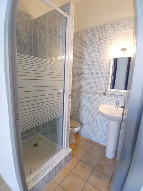 Modern bathroom at Hôtel Quai d'Azur with shower enclosure, toilet, and pedestal sink in Le Grau-du-Roi