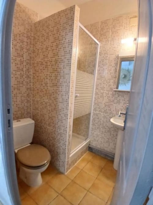 Modern bathroom at Hôtel Quai d'Azur with toilet, shower enclosure, and terracotta tiling