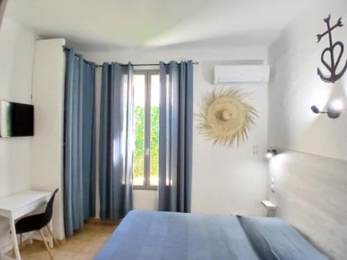 Hôtel Quai d'Azur double room with blue curtains, modern furnishings, and white walls in Le Grau-du-Roi