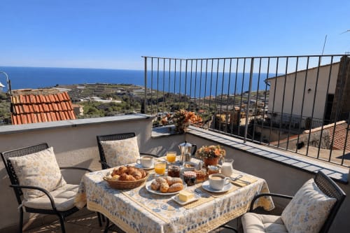 Colazione in terrazza fronte mare all'Agriturismo Il Vecchio Mulino di Terzorio con vista sul mare, dolcetti e succhi