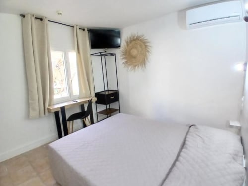 Bright family room at Hôtel Quai d'Azur with bed, desk, TV, window and modern minimalist décor