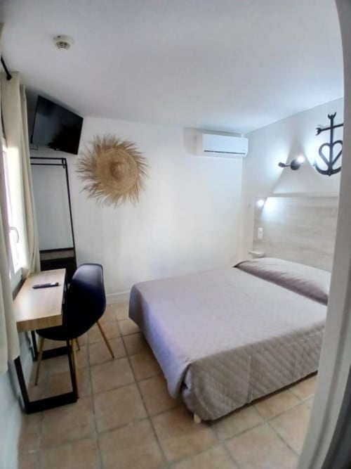 Family room at Hôtel Quai d'Azur in Le Grau-du-Roi with bed, desk, TV, and modern decor